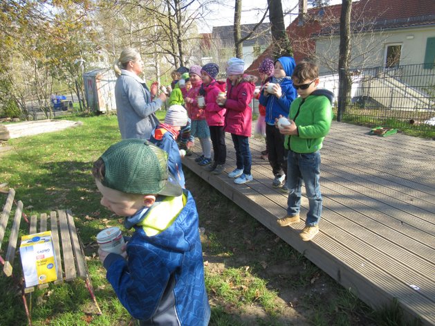 Kinder stehen im Freien au einer Rampe und hören einer Pädagogin zu, die ihnen Spannendes über gesundes Essen erzählt